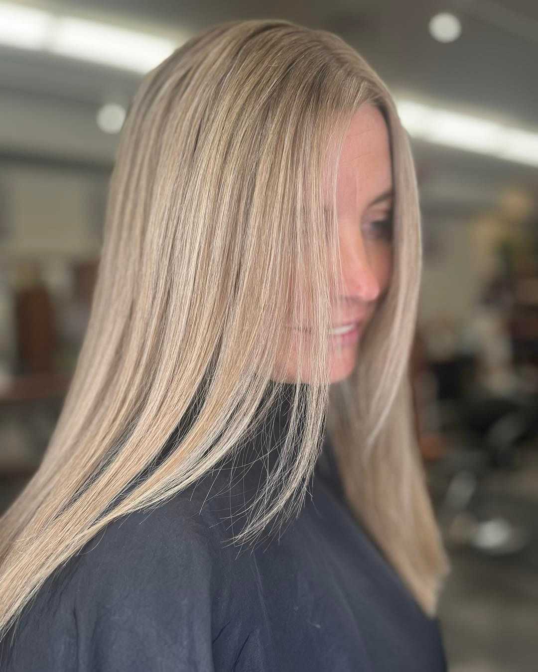 Woman with long, straight blonde hair smiling in a salon.