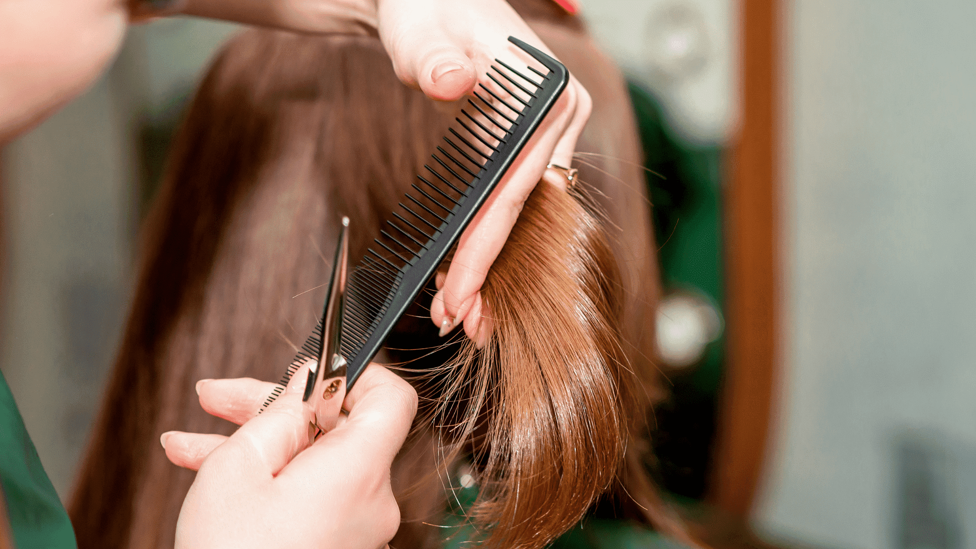 Stylist combing and trimming brown hair with scissors in a salon.