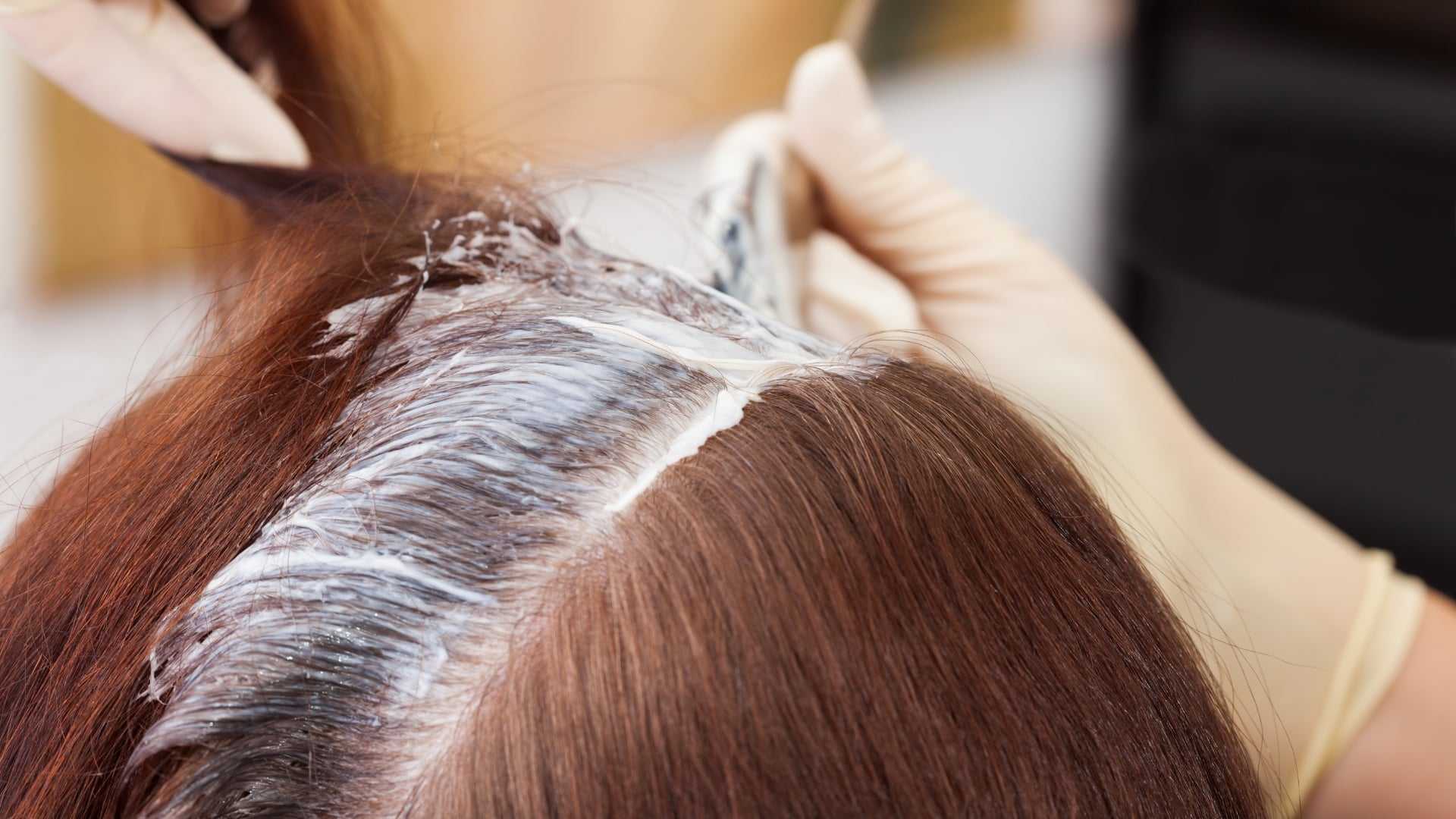 Hair dye being applied to brown hair at a salon.