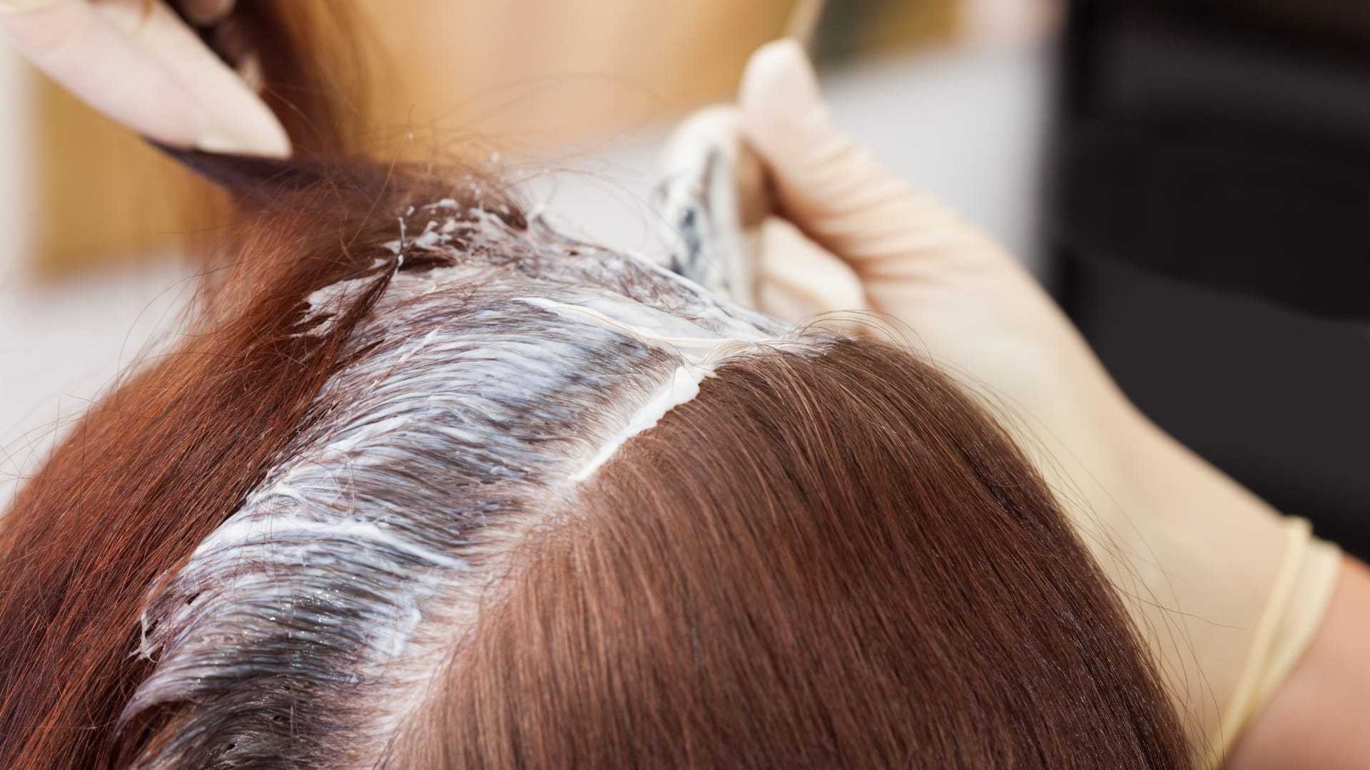 Hair dye being applied to brown hair at a salon.